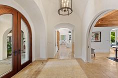 a large hallway with arched doorways leading to the kitchen and dining room area in this home