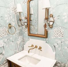 a white sink sitting under a bathroom mirror next to a wall mounted faucet