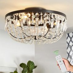 a person holding a remote control in their hand and a chandelier above them