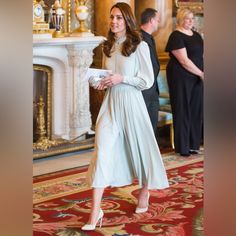 the duke and person are standing in front of a fire place wearing long white dresses