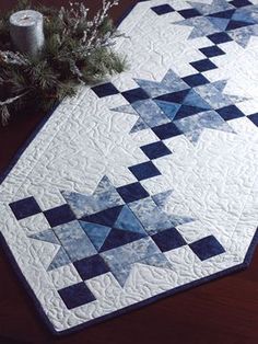 a blue and white quilted table runner on a wooden table next to a roll of toilet paper