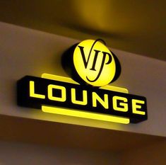 the sign for lounge is lit up with yellow light and black lettering on it's side