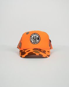 Step up your street style with our exclusive orange camo hat embroidered with a bold black and white logo. Crafted with utmost precision and attention to detail, this exquisite headwear effortlessly combines fashion-forward design with unparalleled comfort. This head turning accessory screams luxury and unique style. The distinctive pins also aides in the trucker’s exceptional rare look. Casual Orange 5-panel Trucker Hat, Orange Curved Brim Sports Hat, Orange Trucker Hat For Streetwear, Casual Orange Trucker Hat For Streetwear, Orange Snapback Trucker Hat For Sports, Orange Curved Brim Baseball Cap For Sports, Orange Snapback Hats For Streetwear, Orange Curved Brim Snapback Hat, Orange Trucker Hat For Sports