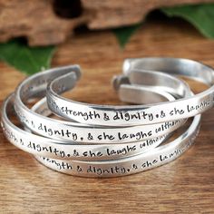 "Take a LOOK at our Website: ANNIEREH.com She is Clothed in Strength and Dignity, Bible Verse Bracelet, PROVERBS 31:25, Scripture Jewelry, Christian Bracelets, Gifts for Her Customize your Cuff with your favorite Bible Verse. Let us know the info for the inside and outside of cuff. This cuff comes in aluminum, copper, or brass with a beautiful decorative texture on the outside. ** Bracelet is approx 6\" long and 1/4\" wide Size 6\" is for average wrist sizes from 6\" to 9\" (MOST COMMON FOR WOME Inspirational Hypoallergenic Silver Bracelets, Adjustable Stamped Bracelets, Handmade Inspirational Silver Bracelets, Nickel-free Inspirational Bracelets, Handmade Inspirational Silver Bracelet, Meaningful Adjustable Silver Bracelets, Adjustable Silver Bracelets With Meaningful Style, Meaningful Silver Adjustable Bracelets, Verse Bracelet