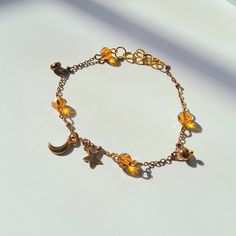 This Beautiful 14k Moon and Star Charm Bracelet is perfect for anyone who loves the moon, stars, and all things astronomy-related! The bracelet has the personalized color options of bronze, pink, or green beads of your choosing and two astronomy pendants; one star and one moon charm. It also comes with a moon and star charm which is a perfect and unique gift for any stargazer in your life! This Beautiful moon and stars, gold charm bracelet is also a part of the Astronomy Collection which is full Bohemian Adjustable Bracelet With Star Charm, Gold Crystal Bracelet With Charms For Jewelry Making, Celestial Charm Bracelet With Star Charm As Gift, Celestial Star Charm Bracelet Gift, Gold Bracelets With Star Charm And Round Beads, Adjustable Celestial Bracelets With Star Charm, Adjustable Star-shaped Celestial Bracelets, Adjustable Celestial Star Bracelet, Celestial Bracelet With Star Charm