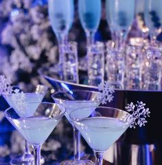 several martini glasses lined up on a table with snowflakes and silverware in them