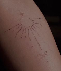 a close up of a person's arm with small stars on it and the sun in the background