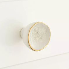 a white and gold knob on a white wall