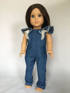 a doll with blue overalls and white lace on her collar is standing in front of a white background