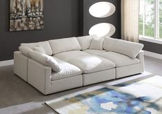 a living room with a large sectional couch in the center and rug on the floor