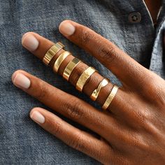 a woman's hand with five gold rings on her fingers and one ring in the middle