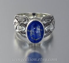 "GUARDIAN ANGELS sterling silver ring was inspired by Medieval art and features two angels - one on each side of the shank. It is adorned with a natural lapis lazuli cabochon (oval 14x10 mm, deep royal blue color). Oxidation adds contrast to the engraved relief. There is the artist mark and .925 for sterling silver stamped inside of the shank. Made to order in the size specified by the customer. Available in any size from 8 to 14. The same design can be made in smaller sizes (5 to 8) too: www.et Elegant Winged Rings As Gifts, Elegant Winged Rings For Gifts, Elegant Sterling Silver Winged Rings, Spiritual Winged Sterling Silver Jewelry, Sterling Silver Winged Rings In Silver, Engraved Winged Sterling Silver Jewelry, Gold Engagement Ring Simple, Rose Gold Engagement Ring Simple, Daylight Ring