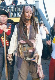 a man dressed up as captain jack sparrow on the deck of a ship with other people