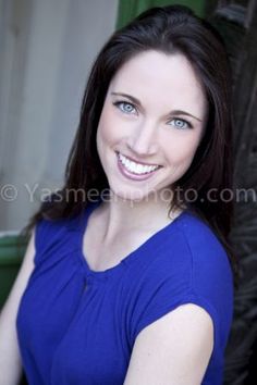 a woman in a blue shirt smiling at the camera