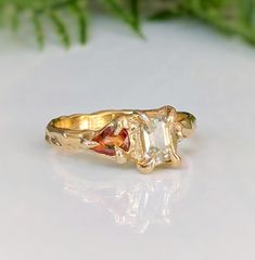 a yellow gold ring with an orange and white diamond in the center on a table