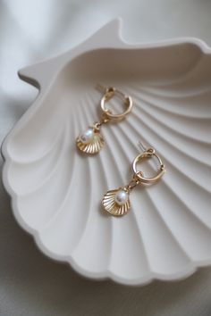 Featuring gold filled hoops adorned with a freshwater pearl and a charming gold filled shell dangle, these earrings will add a touch of seaside style to any outfit. Perfect for beach babes Material: Gold filled, freshwater pearls Size: 13mm hoop, 11mm shell dangle, organic shape rice pearl (size may vary) Shell-shaped Pearl Earrings With Pearl Charm, Pearl Shell Earrings With Pearl Charm, Ocean-inspired Pearl Shell With Pearl Drop, Ocean-inspired Pearl Drop Shell, Ocean-inspired Pearl Drop Dangle Jewelry, Ocean-inspired Dangle Pearl Drop Jewelry, Ocean-inspired Pearl Drop Earrings As A Gift, Ocean-inspired Pearl Drop Earrings, Gold Dangle Shell Earrings With Pearl Drop