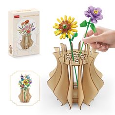 a hand is holding a flower in a vase made out of wooden sticks and paper