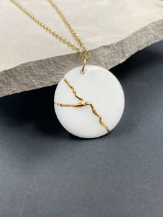 "Handmade porcelain kintsugi pendant necklace. Inspired by KINTSUGI. A perfect anniversary gift or encouragement gift. Kintsugi is a Japanese art of repairing broken pottery with gold. Ceramics once broken are glued back together with lacquer and finished with gold to bring beauty to what was once shattered. Kintsugi honors brokenness and challenges in life -- it celebrates beauty in the broken. This metaphor we can apply to ourselves. We can mend and transform what has broken us, and we can fin Minimalist White Jewelry For Anniversary, Minimalist White Jewelry For Anniversary Gift, Minimalist Handmade Necklace For Keepsake, Minimalist Handmade Keepsake Necklace, White Round Pendant Necklaces For Anniversary Gift, White Round Pendant Necklace For Anniversary, Minimalist White Keepsake Necklace, Kintsugi Necklace, Kintsugi Aesthetic