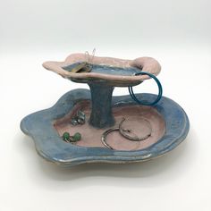 a blue and pink ceramic dish with jewelry on it