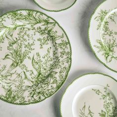 four green and white plates with floral designs on them, all sitting next to each other