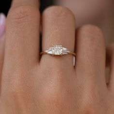 a woman's hand with a diamond ring on top of her finger and an engagement band