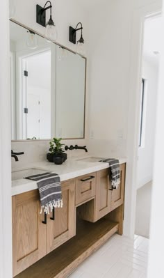 a bathroom with two sinks, mirrors and towels on the counter top in front of it