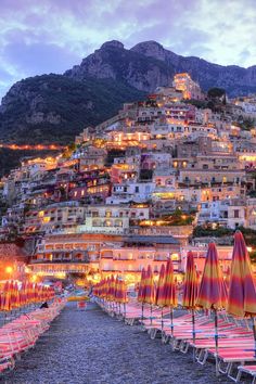 an image of a beach with umbrellas and buildings on the hill in the background