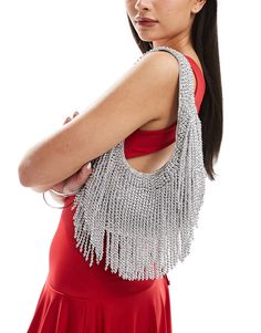 a woman in a red dress is wearing a silver fringed handbag on her shoulder