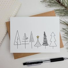 a christmas card with trees on it next to a pen