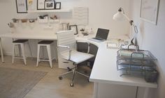 a white desk with two chairs and a laptop on top of it in a room