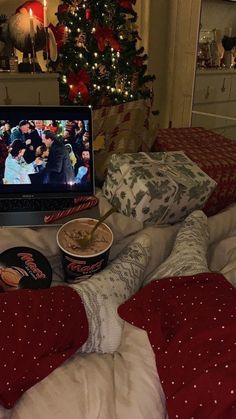 an open laptop computer sitting on top of a bed next to pillows and christmas decorations