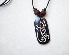 a black and white pendant with a lizard on it's side hanging from a cord