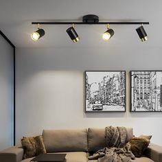 a living room with two couches and three lights on the wall above each sofa