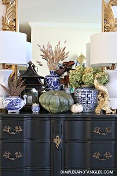 a black dresser topped with lots of vases and lamps