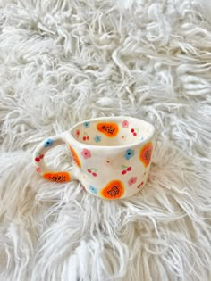 a cup sitting on top of a white fur covered floor