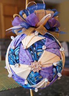 an ornament hanging from a wooden stick with purple and blue decorations on it