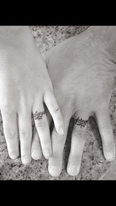 two people holding hands with tattoos on their fingers