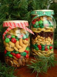 two jars filled with candy and nuts on top of a table next to a christmas tree