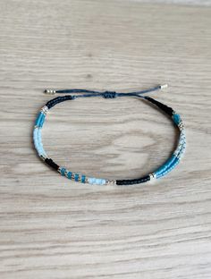 A delicate and elegant string bracelet made of two strands of black, silver and blue miyuki beads. ☆ ☆ ☆ SIZING☆ ☆ ☆ This bracelet is easily adjustable thanks to a macrame slide knot. It should fit most adults and teens but please message me if you think you need a smaller or larger fit. It is about 5 inches when fully tightened and about 9 inches when expanded. ☆ ☆ ☆ TAKING CARE OF YOUR BRACELET ☆ ☆ ☆ This bracelet is waterproof but it is best to avoid prolonged exposure with salt, chlorine, pe Blue Beaded Minimalist Friendship Bracelets, Minimalist Blue Friendship Bracelets, Minimalist Handmade Blue Friendship Bracelets, Miyuki Bracelet, Cord Jewelry, Minimalist Bracelet, Miyuki Beads, String Bracelet, Boho Gifts