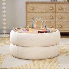 a child's toy train set sitting on top of a white ottoman in a room