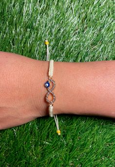 This is our off-white adjustable bracelet featuring an infinity evil eye charm. It is adjustable to fit various wrist sizes from 6.5 inches-9 inches. The model above is a 6.5 inch wrist size. The bracelet is lightweight and durable. It is made from Nylon threading imported from Mexico.  At Cari Boutique, we make our bracelets with the mindset of exceeding our customers expectations! We are a women run business and all our unique trendy bracelets are made by hand, day by day. Interested in our items and looking for more jewelry options? Check out our Instagram for sneak peeks of upcoming jewelry @Cariboutiquenyc Thank you for your interest & if you have any questions please don't hesitate to contact us through our email; @cariboutiquenyc@gmail.com **We ship USPS First Class with Free Shippi Infinity Evil Eye Bracelet, Adjustable White Infinity Jewelry, Adjustable Infinity Friendship Bracelets, Adjustable Gold Evil Eye Bracelet For Beach, Adjustable Evil Eye Bracelet For Friendship, Adjustable Infinity Bracelet, Trendy Adjustable Infinity Bracelet, Adjustable Casual Evil Eye Jewelry, Adjustable Evil Eye Casual Jewelry