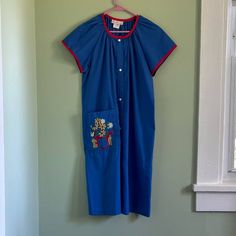 This 50s vintage Cotillion house dress is a size small. The dress is blue with red detailing and a floral embroidery pattern on front pocket. It has snap buttons down the front and falls to midi length. It has a union tag, is USA made and is a polyester cotton blend. This dress is something I imagine Snow White would wear while making pies and talking to her animal friends. It's a gorgeous piece with cottagecore vibes and is in good vintage condition.  Flaws (pictured)  Some damage on one of the shoulders All measurements are laying flat and approximate Armpit to armpit 22 inches Length 41 inches Weight 8 oz Vintage Blue Dresses With Pockets, Blue Vintage Dresses With Pockets, Vintage Blue Embroidered Dresses, How To Make Pie, Floral Embroidery Patterns, 50s Vintage, House Dress, Blue House, Floral Embroidery