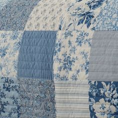 a blue and white quilt with flowers on it's side, next to a pillow