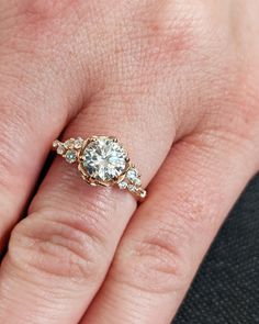 a woman's hand with a diamond ring on top of her finger and two diamonds in the middle