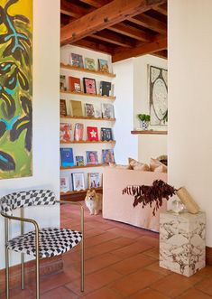 a living room filled with furniture and bookshelves next to a painting on the wall