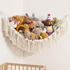 there are many stuffed animals in the hammock on the wall above the crib