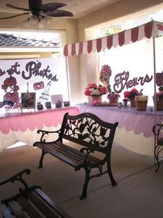 a bench sitting in front of a table with flowers on it and two signs behind it