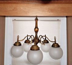 a chandelier with five white glass globes hanging from it's center