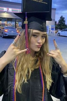 a woman in graduation cap and gown holding her fingers up to the side with one hand