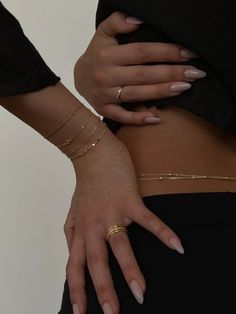 a woman with her hands on her hip wearing gold bracelets and ring set,